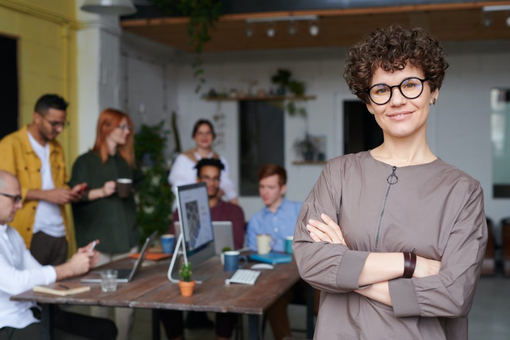 Woman in office filled with employees who can be used as the face of an buyer persona