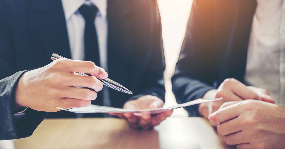 a person holding a pen over a piece of paper